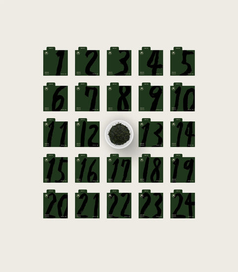 A coffee gift set presentation including an open dark green box with printed details, a red and dark green decorated box, two small black cards, and loose coffee beans on a light beige background.